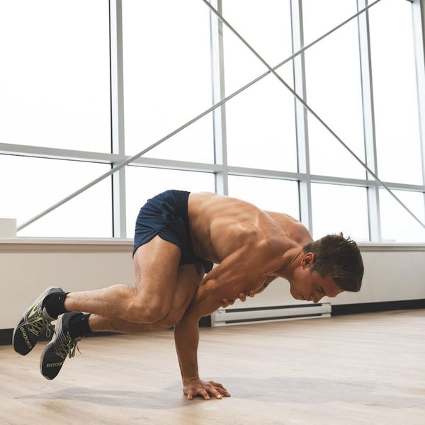 Man performing a strength exercise in a modern, dark gym.